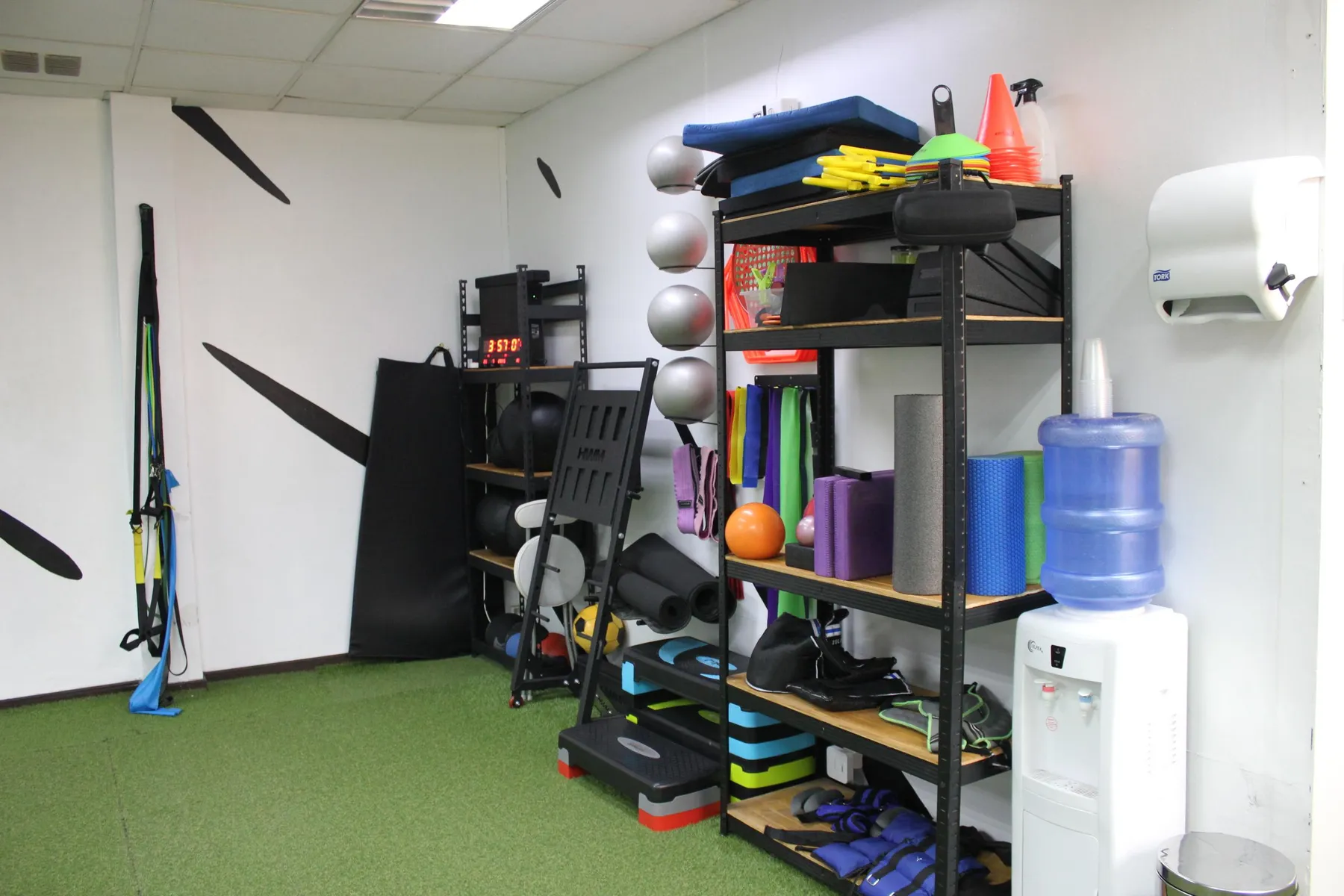 Estantería con implementos de rehabilitación: rodillos de espuma, balones, bandas elásticas y conos